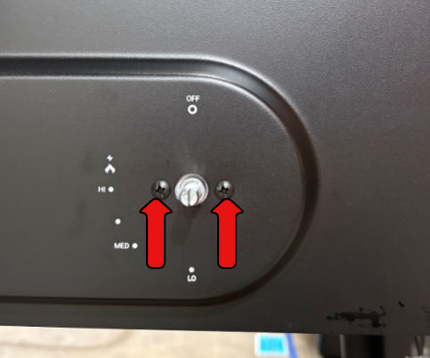 Image with two red arrows pointing to the screws under the burner knob that need to be removed. 